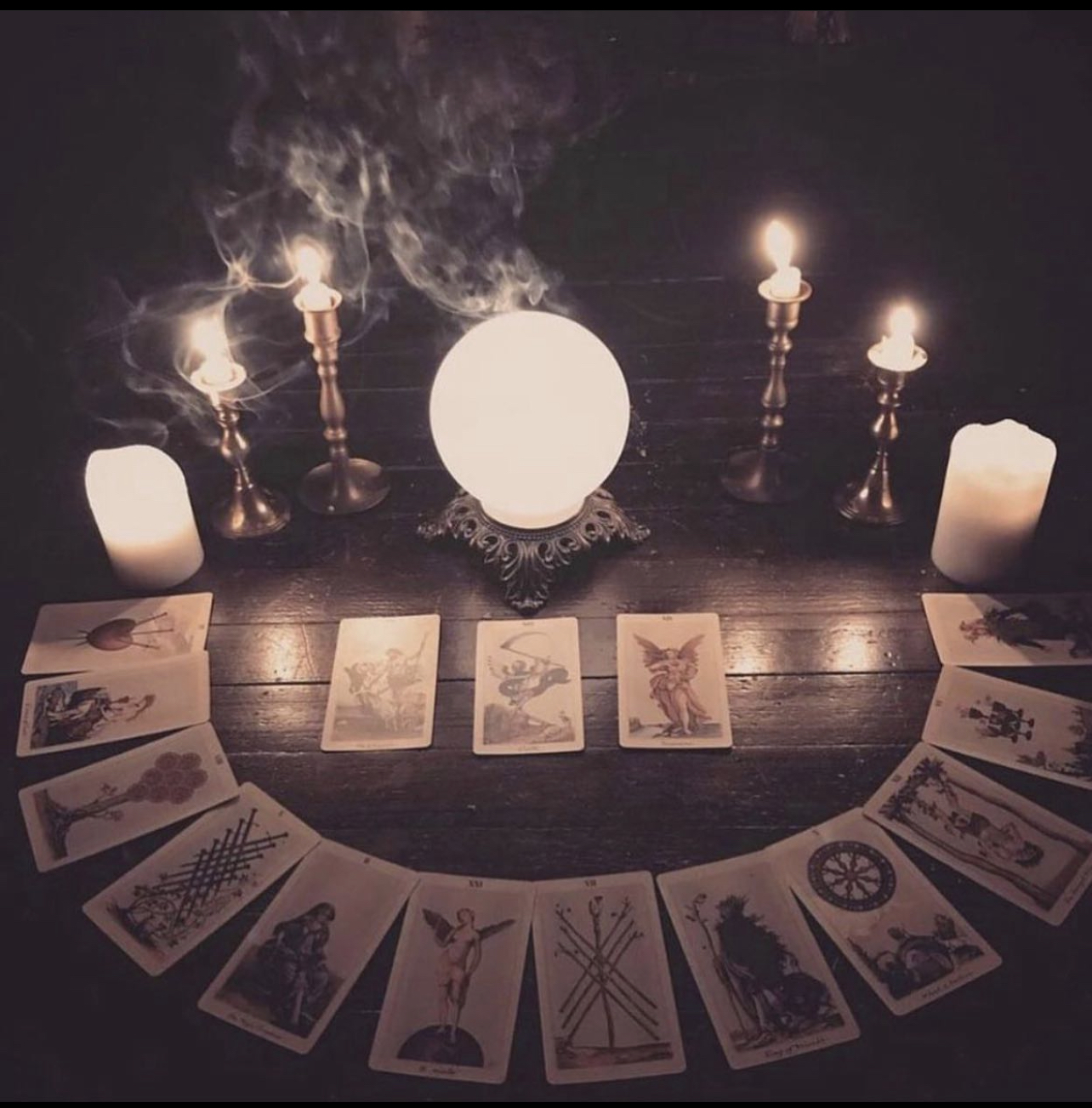 Tarot Card layout in front of lighted candles and crystal ball