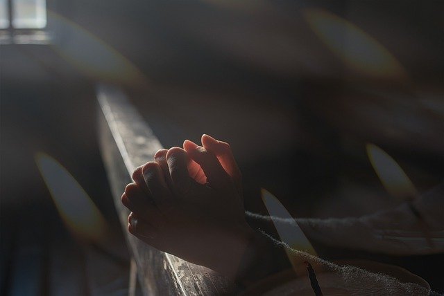 Hands folded in prayer by window