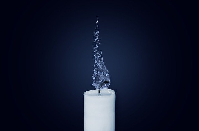 Candle with water flame against dark blue background